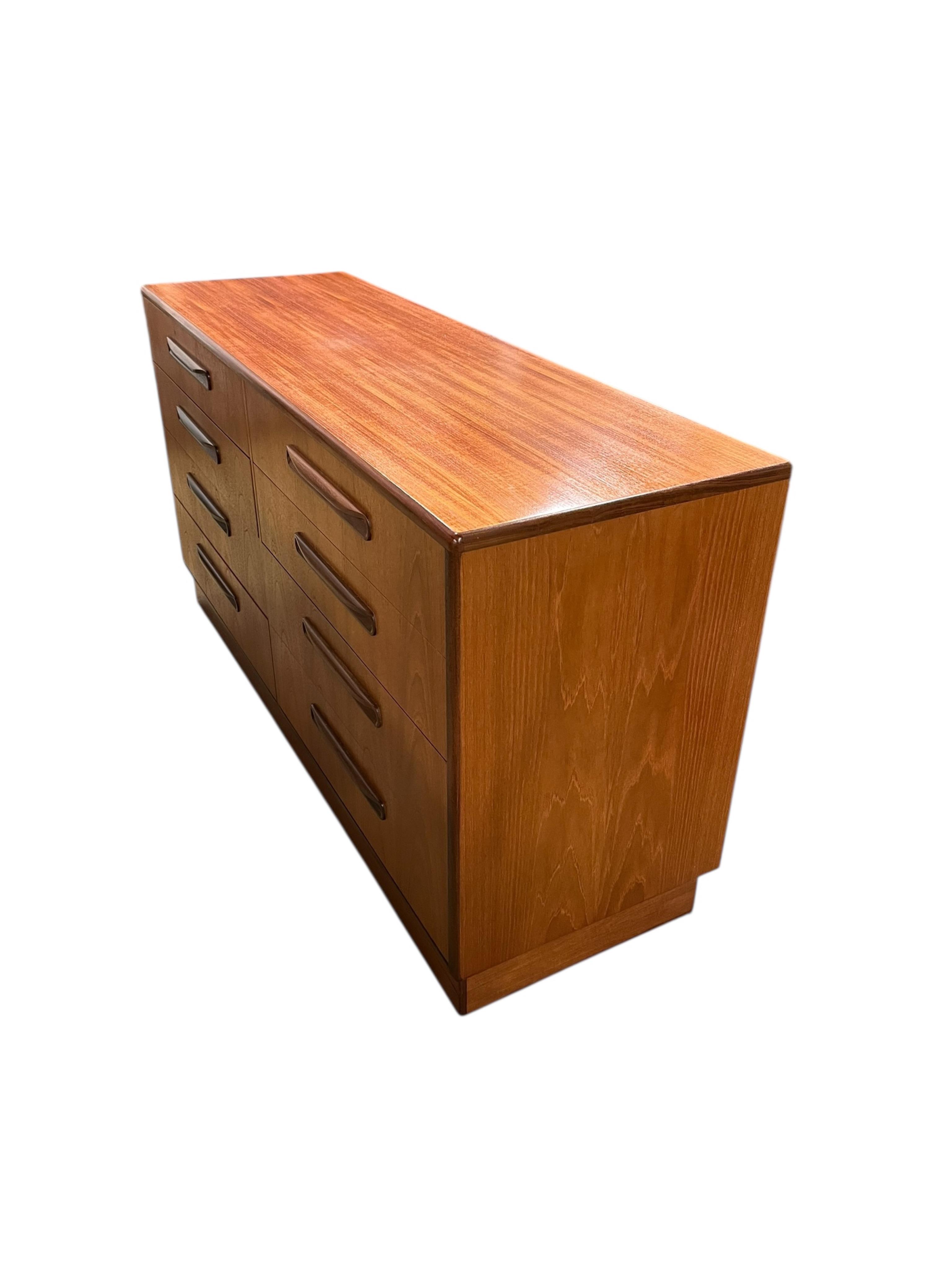 A mid century G Plan Fresco teak bedroom suite comprising a three door wardrobe, a two door wardrobe, two six drawer chests, dressing table, headboard and a pair of bedside chests